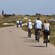 People ride bikes along a road in the countryside as others walk in the opposite direction